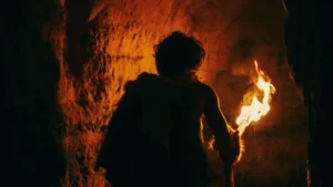 primeval-caveman-with-fire-torch-exploring-cave.webp.webp